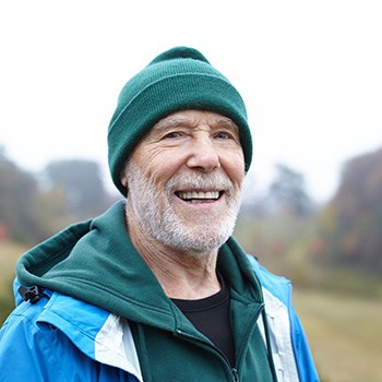 An older, smiling man having a walk in a rural area