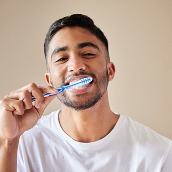 Man smiling while brushing his teeth